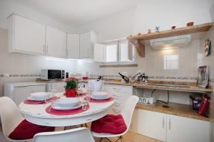 a white kitchen with a table with red cushioned chairs at Páteo da Várzea 4 in Colares