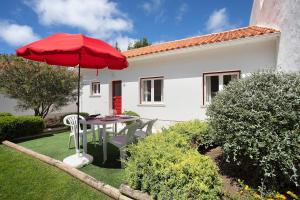 a patio with a table and a red umbrella at Páteo da Várzea 4 in Colares