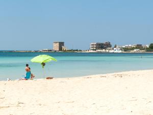a person sitting in a chair under an umbrella on the beach at Villa Tetta sul mare in Torre Lapillo