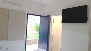 a room with a door and a television on the wall at Hotel Lagoinha in Ubatuba