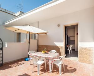 a patio with a table and chairs and an umbrella at Villa Tetta sul mare in Torre Lapillo