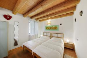 a bed in a room with white walls and wooden ceilings at Villa Cleila Verde B in San Vito di Cadore
