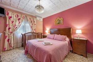 a bedroom with a bed with pink walls at Como En Casa Jerez in Jerez de la Frontera +21 photos
