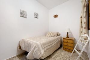 a white bedroom with a bed and a night stand at Casa Maria Cosme in Los Realejos