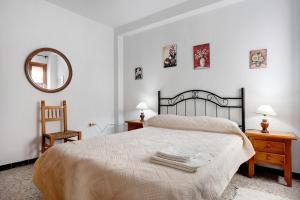 a bedroom with a bed and a mirror and a chair at Casa Ángela in Conil de la Frontera