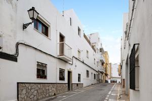 an empty street in an alley with white buildings at Casa Ángela in Conil de la Frontera