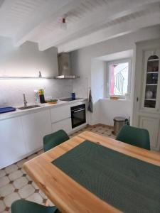a kitchen with a wooden table and green chairs at Maison de campagne in Séneujols