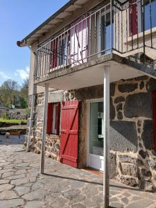 a building with a red door and a balcony at Maison de campagne in Séneujols