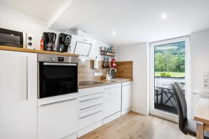 a kitchen with white cabinets and a large window at Ferienwohnung Kurparkblicksauerland in Lennestadt