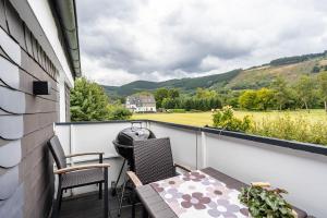 a balcony with a table and chairs and a view of a field at Ferienwohnung Kurparkblicksauerland in Lennestadt