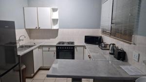 a kitchen with white cabinets and a stove top oven at Pendleberry Unit 85 in Warmbaths