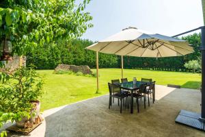 a table and chairs under an umbrella in a garden at Chambre Chene in Mauléon-dʼArmagnac