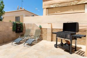 a grill with chairs and a tv on a patio at Villa Palomas in Nerja