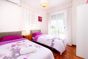 two beds in a bedroom with pink and purple sheets at Villa Palomas in Nerja +29 photos