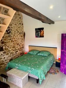 a bedroom with a green bed and a stone wall at Gite Cosy Forme et Bien-etre in Masseret +26 photos