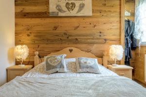 a bedroom with a bed with wooden walls and two lamps at La Petite Chaumière avec sauna in Saint-Maurice-sur-Moselle