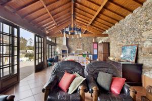 a living room with two leather chairs and a stone wall at Casa de Barqueiros in Barqueiros