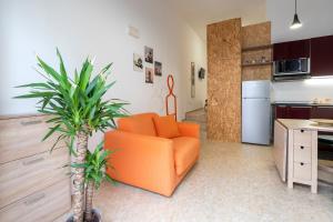 a living room with an orange chair and a kitchen at La Casa di Laura in Putignano +6 photos