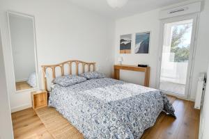 a bedroom with a bed with a blue comforter and a window at Senyo Cocoon in Seignosse