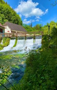 a waterfall in front of a wooden building at Ferienwohnung am Kappenturm in Hayingen