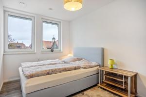 a bedroom with a bed and two windows at Ferienwohnung am Kappenturm in Hayingen