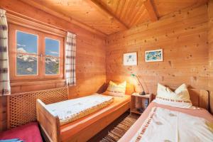 a bedroom with two beds in a log cabin at Ferienhaus Rauchegg - Seeblick in San Pancrazio dʼUltimo