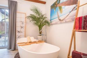 a bathroom with a bath tub and a palm tree at Ferienwohnung Relax in Sigmarszell +16 photos