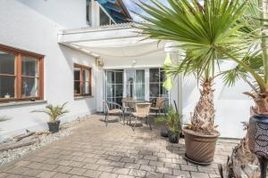 a patio with palm trees and a table at Ferienwohnung Relax in Sigmarszell