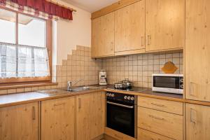 a kitchen with wooden cabinets and a sink and a microwave at Ciasa Tlara App Lisa in San Vigilio Di Marebbe +14 photos