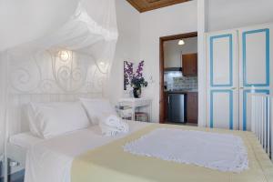 a bedroom with a white bed and a kitchen at Areti Orfeas Studio in Vasilikos