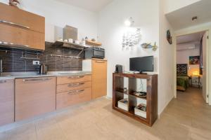 a kitchen with wooden cabinets and a flat screen tv at Casa Cò in Costa Rei +18 photos