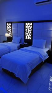 two beds in a room with blue lights at فلل لوسيرن in Khamis Mushayt