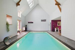 an indoor swimming pool in a room with a ceiling at Gîte La Clémençaie in Réminiac