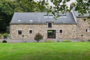 a stone house with windows on top of a yard at Gîte La Clémençaie in Réminiac