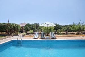 a swimming pool with two chairs and an umbrella at Las Tres Palmeras in Güimar
