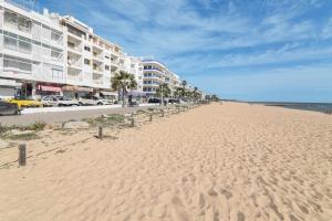 a sandy beach with a row of buildings and the ocean at Sail Away in Quarteira