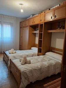 two beds in a room with wooden cabinets at Montes de Alhama Il in Soria +2 photos