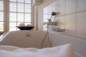 a bath tub with a shower in a bathroom at Landhaus Sommerland in Uelvesbüll