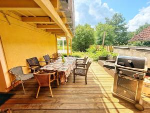 a wooden deck with a table and chairs and a grill at Wohnung 6 und 7 in Burghaslach