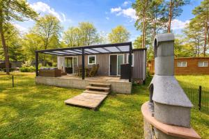 a tiny house in a garden with a roof at Luxe chalet voor gezinnen in familiepark Goolderheide met openlucht zwembaden en ruim overdekt terras 24m2 in Bocholt