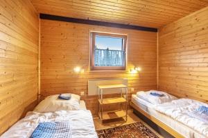 two beds in a wooden room with a window at Feriendorf Rechbergblick, Haus 29 in Bernau im Schwarzwald