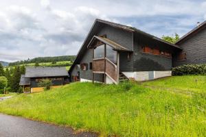 a house on a grassy hill next to a road at Feriendorf Rechbergblick, Haus 29 in Bernau im Schwarzwald