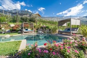 a swimming pool in a garden with flowers at Apfel Chalet Feldhof in Caines