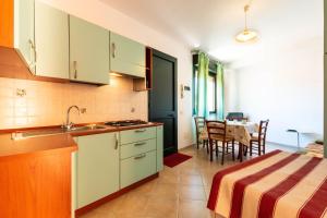 a kitchen with white cabinets and a dining room with a table at Appartamenti Cavour Codice E in Villasimius