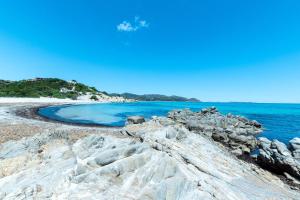a beach with blue water and rocks on the shore at Appartamenti Cavour Codice E in Villasimius