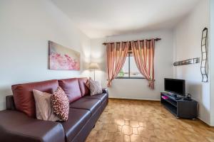 a living room with a leather couch and a television at Cabo de Sagres -2 bedroom apartment in Sagres