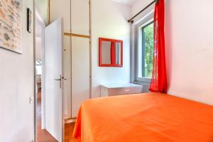 a bedroom with an orange bed and a window at Villetta Serena in Procchio