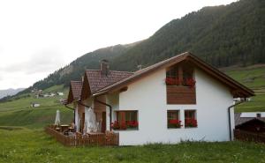 a white house in a field with a mountain at Rieglhof Apartment Maisel in Curon Venosta