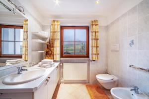 a bathroom with two sinks and a toilet and a window at Rieglhof Apartment Maisel in Curon Venosta +12 photos