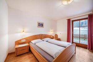 a bedroom with a wooden bed with a window at Rieglhof Apartment Maisel in Curon Venosta